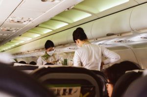 flight attendants wearing face mask while standing on the aisle of an airplane